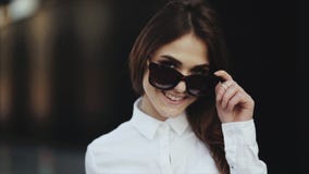 Портрет привлекательной молодой женщины усмехаясь на пляже извлекает солнечные очки крутые видеоматериал Портрет привлекательной молодой женщины усмехаясь на пляже извлекает солнечные очки крутые видеоматериал