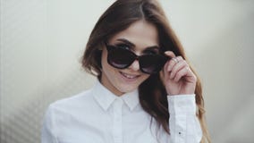 Портрет привлекательной молодой женщины усмехаясь на пляже извлекает солнечные очки крутые акции видеоматериалы Портрет привлекательной молодой женщины усмехаясь на пляже извлекает солнечные очки крутые акции видеоматериалы