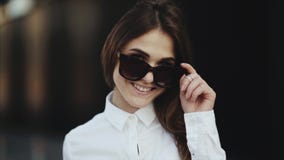 Портрет привлекательной молодой женщины усмехаясь на пляже извлекает солнечные очки крутые акции видеоматериалы Портрет привлекательной молодой женщины усмехаясь на пляже извлекает солнечные очки крутые акции видеоматериалы