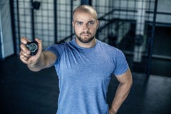 Портрет серьезного тренера спорт с лысой головой Показывает секундомер в камере в спортзале разминка была успешна одетый внутри стоковое фото rf Портрет серьезного тренера спорт с лысой головой Показывает секундомер в камере в спортзале разминка была успешна одетый внутри стоковое фото rf