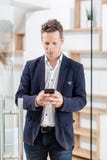 Портрет современного бизнесмена с умным положением телефона в современном офисе стоковые изображения Портрет современного бизнесмена с умным положением телефона в современном офисе стоковые изображения