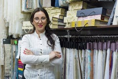 Портрет счастливого предпринимателя женщины с пересеченными оружиями в внутреннем магазине тканей, образцами ткани предпосылки Тк стоковые изображения rf Портрет счастливого предпринимателя женщины с пересеченными оружиями в внутреннем магазине тканей, образцами ткани предпосылки Тк стоковые изображения rf