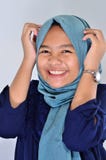 Портрет счастливой азиатской девушки нося голубое hijab усмехаясь на вас и касаясь haed ей стоковое изображение Портрет счастливой азиатской девушки нося голубое hijab усмехаясь на вас и касаясь haed ей стоковое изображение