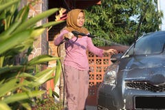 Портрет счастливой чистки автомобиля женщин hijab - извлекающ мыло с водой, используя шланг сада и оружие брызг стоковые фотографии rf Портрет счастливой чистки автомобиля женщин hijab - извлекающ мыло с водой, используя шланг сада и оружие брызг стоковые фотографии rf