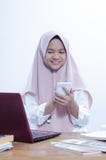 Портрет уверенной молодой женщины smilling при работе в ее офисе с ее красным ноутбуком, и пишущ на ее тетради стоковое фото Портрет уверенной молодой женщины smilling при работе в ее офисе с ее красным ноутбуком, и пишущ на ее тетради стоковое фото