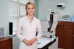 Портрет усмехаясь красивого глазного врача стоя с ophthalmologic прибором в шкафе стоковая фотография Портрет усмехаясь красивого глазного врача стоя с ophthalmologic прибором в шкафе стоковая фотография