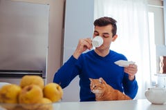 Портрет чая молодого человека выпивая с котом на кухне стоковые фото Портрет чая молодого человека выпивая с котом на кухне стоковые фото