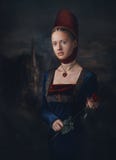 Портрет шикарной девушки в платье и головном уборе эпохи средневековья Медальон в форме сердца Держать красную розу в руках стоковые изображения Портрет шикарной девушки в платье и головном уборе эпохи средневековья Медальон в форме сердца Держать красную розу в руках стоковые изображения