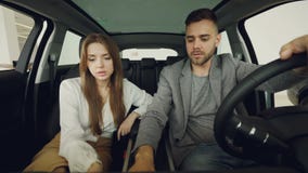 Потенциальные покупатели автомобиля экономно расходуют и жена проверяет усаживание автомобиля внутреннее в передних местах держа акции видеоматериалы Потенциальные покупатели автомобиля экономно расходуют и жена проверяет усаживание автомобиля внутреннее в передних местах держа акции видеоматериалы