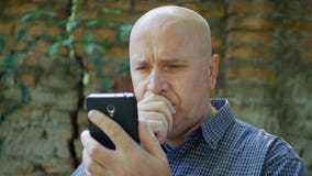 Потревоженный человек смотря к мобильному тексту разочарованному и беспомощному стоковые фотографии rf Потревоженный человек смотря к мобильному тексту разочарованному и беспомощному стоковые фотографии rf