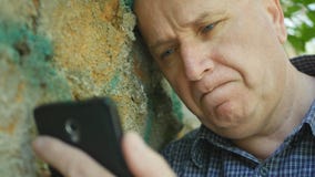Потревоженный человек смотря к мобильному телефону разочаровал и беспомощный стоковые фотографии rf Потревоженный человек смотря к мобильному телефону разочаровал и беспомощный стоковые фотографии rf