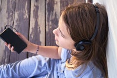 Предназначенная для подростков девушка с наушниками наслаждаясь музыкой от smartphone outdoors стоковые фотографии rf Предназначенная для подростков девушка с наушниками наслаждаясь музыкой от smartphone outdoors стоковые фотографии rf