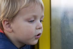 Прелестный маленький белокурый мальчик ребенк сидя около окна и выглядя внешний стоковая фотография rf Прелестный маленький белокурый мальчик ребенк сидя около окна и выглядя внешний стоковая фотография rf