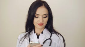 Привлекательный женский доктор используя мобильный телефон на предпосылке 4K сток-видео Привлекательный женский доктор используя мобильный телефон на предпосылке 4K сток-видео