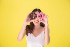 Привлекательная азиатская женщина держа 2 donuts с милым усмехаясь выражением над желтой предпосылкой стоковая фотография Привлекательная азиатская женщина держа 2 donuts с милым усмехаясь выражением над желтой предпосылкой стоковая фотография