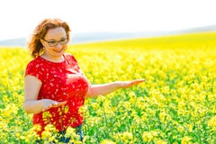 Привлекательная женщина в красном платье представляя в поле рапса семени масличной культуры стоковое фото rf Привлекательная женщина в красном платье представляя в поле рапса семени масличной культуры стоковое фото rf