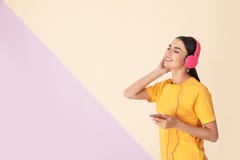 Привлекательная женщина с мобильным телефоном наслаждаясь музыкой в наушниках на предпосылке цвета стоковое фото rf Привлекательная женщина с мобильным телефоном наслаждаясь музыкой в наушниках на предпосылке цвета стоковое фото rf