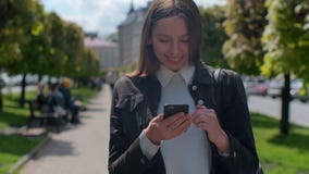 Привлекательная молодая женщина идя на солнечные улицы города и беседуя с друзьями, радостной девушкой хипстера используя мобильн видеоматериал Привлекательная молодая женщина идя на солнечные улицы города и беседуя с друзьями, радостной девушкой хипстера используя мобильн видеоматериал
