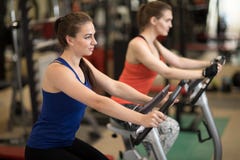 Привлекательные маленькие девочки в одежде спорт работая на спортзале bicycles Стоковое Фото Привлекательные маленькие девочки в одежде спорт работая на спортзале bicycles Стоковое Фото