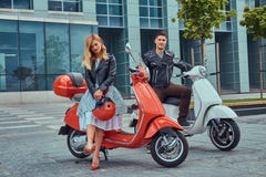 Привлекательные романтичные пары, красивый человек и сексуальная женщина, стоя с 2 ретро итальянскими самокатами против a стоковые фото Привлекательные романтичные пары, красивый человек и сексуальная женщина, стоя с 2 ретро итальянскими самокатами против a стоковые фото