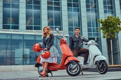 Привлекательные романтичные пары, красивый человек и сексуальная женщина, стоя с 2 ретро итальянскими самокатами против a стоковая фотография Привлекательные романтичные пары, красивый человек и сексуальная женщина, стоя с 2 ретро итальянскими самокатами против a стоковая фотография