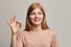 Приятная возбужденная женщина со знаком ок показа испуская лучи улыбки стоковые фотографии rf Приятная возбужденная женщина со знаком ок показа испуская лучи улыбки стоковые фотографии rf