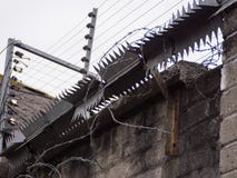 Провод бритвы, электрическая загородка и шипы металла на стене стоковое изображение rf Провод бритвы, электрическая загородка и шипы металла на стене стоковое изображение rf