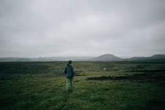 Прогулки Hiker или путешественника в зеленом поле в Исландии стоковое изображение rf Прогулки Hiker или путешественника в зеленом поле в Исландии стоковое изображение rf