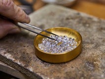 Продукция ювелирных изделий Диамант, который держат щипчики на фоне диамантов стоковое изображение rf Продукция ювелирных изделий Диамант, который держат щипчики на фоне диамантов стоковое изображение rf