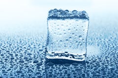Прозрачный куб льда с отражением на синем стекле с водой падает Стоковые Изображения RF Прозрачный куб льда с отражением на синем стекле с водой падает Стоковые Изображения RF