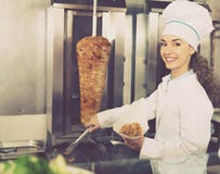 Профессиональный женский кашевар с зажаренным мясом на вертеле для kebab Стоковое Фото Профессиональный женский кашевар с зажаренным мясом на вертеле для kebab Стоковое Фото