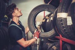 Профессиональный механик автомобиля выбирая новую автошину в обслуживании ремонта автомобилей Стоковые Фото Профессиональный механик автомобиля выбирая новую автошину в обслуживании ремонта автомобилей Стоковые Фото