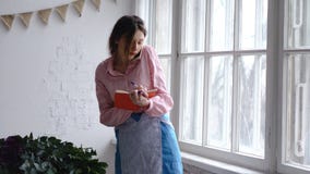 Профессиональный флорист говорит на примечаниях телефона и сочинительства к тетради стоковая фотография rf Профессиональный флорист говорит на примечаниях телефона и сочинительства к тетради стоковая фотография rf