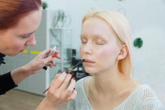 Процесс делать макияж Художник макияжа работая с щеткой на модельной стороне стоковое фото Процесс делать макияж Художник макияжа работая с щеткой на модельной стороне стоковое фото