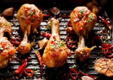 Пряные зажаренные куриные ножки, drumsticks с дополнением перцев chili, чеснок и травы на плите гриля, взгляде сверху стоковое фото rf Пряные зажаренные куриные ножки, drumsticks с дополнением перцев chili, чеснок и травы на плите гриля, взгляде сверху стоковое фото rf