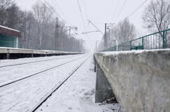 Пустой железнодорожный вокзал в сильном снегопаде с сильным туманом Железнодорожные рельсы идут прочь в белый туман снега Концепц стоковое изображение rf Пустой железнодорожный вокзал в сильном снегопаде с сильным туманом Железнодорожные рельсы идут прочь в белый туман снега Концепц стоковое изображение rf