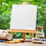 Пустой холст на мольберте, художнических paintbrushes и трубках краски Стоковая Фотография RF Пустой холст на мольберте, художнических paintbrushes и трубках краски Стоковая Фотография RF