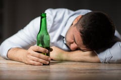 Пьяный человек при пивная бутылка лежа на таблице на ноче стоковое изображение rf Пьяный человек при пивная бутылка лежа на таблице на ноче стоковое изображение rf