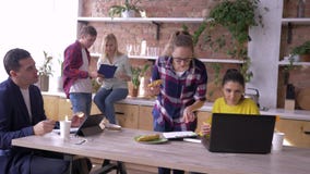 Работая команда успешных молодых предпринимателей ел и работающ с планшетами и ноутбуками в кухне во время делать акции видеоматериалы Работая команда успешных молодых предпринимателей ел и работающ с планшетами и ноутбуками в кухне во время делать акции видеоматериалы
