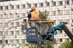 Работник в ведре подъема во время установки поляка металла с уличным фонарем, фонарным столбом улицы с двойной головой стоковые фотографии rf Работник в ведре подъема во время установки поляка металла с уличным фонарем, фонарным столбом улицы с двойной головой стоковые фотографии rf