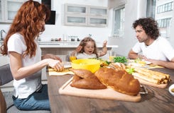 Радостные родители и дочь есть здоровую еду в кухне стоковая фотография rf Радостные родители и дочь есть здоровую еду в кухне стоковая фотография rf