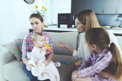 Разговаривать няни с матерью детей Она держит младенца в ее оружиях Мать детей бранит медсестру стоковые изображения Разговаривать няни с матерью детей Она держит младенца в ее оружиях Мать детей бранит медсестру стоковые изображения