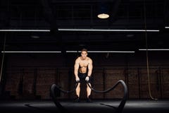 Разминка человека фитнеса с сражением ropes на спортзале тело приспособленное учебным упражнени в клубе торс стоковое фото Разминка человека фитнеса с сражением ropes на спортзале тело приспособленное учебным упражнени в клубе торс стоковое фото
