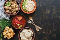 Разнообразие русская еда, борщ, замаринованные грибы, вареники, sauerkraut, гренки на темной деревенской предпосылке Взгляд сверх стоковая фотография rf Разнообразие русская еда, борщ, замаринованные грибы, вареники, sauerkraut, гренки на темной деревенской предпосылке Взгляд сверх стоковая фотография rf
