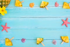 Рамка сделанная ручек, морских звёзд и раковин popsicle ананаса на деревянном цвете сини планки Стоковые Изображения RF Рамка сделанная ручек, морских звёзд и раковин popsicle ананаса на деревянном цвете сини планки Стоковые Изображения RF