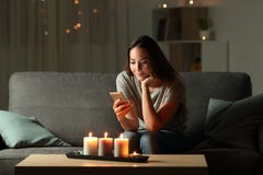 Расслабленная девушка используя телефон в ноче с свечой освещает стоковая фотография rf Расслабленная девушка используя телефон в ноче с свечой освещает стоковая фотография rf