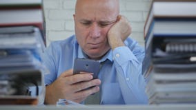 Расстроенный бизнесмен смотря к сообщению мобильного телефона с разочарованной ориентацией стоковая фотография rf Расстроенный бизнесмен смотря к сообщению мобильного телефона с разочарованной ориентацией стоковая фотография rf