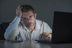 Расточительствованная и уставшая работа человека предпринимателя ночная на столе ноутбука офиса вымотанном и сонномся в финансово стоковые изображения Расточительствованная и уставшая работа человека предпринимателя ночная на столе ноутбука офиса вымотанном и сонномся в финансово стоковые изображения