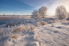 Реальная русская зима Ландшафт зимы утра морозный с ослеплять белыми снегом и изморозью, рекой и насыщенным голубым небом стоковая фотография rf Реальная русская зима Ландшафт зимы утра морозный с ослеплять белыми снегом и изморозью, рекой и насыщенным голубым небом стоковая фотография rf