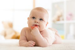 Ребенок младенца маленький сдерживает teether лежа на пеленке weared кроватью стоковые фотографии rf Ребенок младенца маленький сдерживает teether лежа на пеленке weared кроватью стоковые фотографии rf